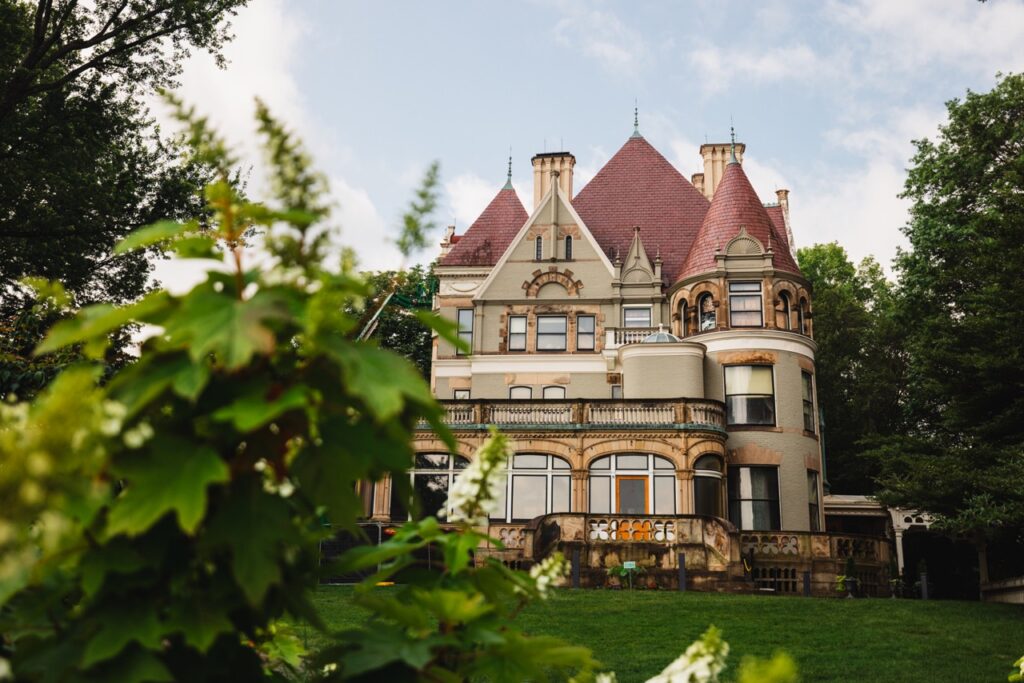 The Clayton house of teh Frick family with tall red roofs and trees all around.