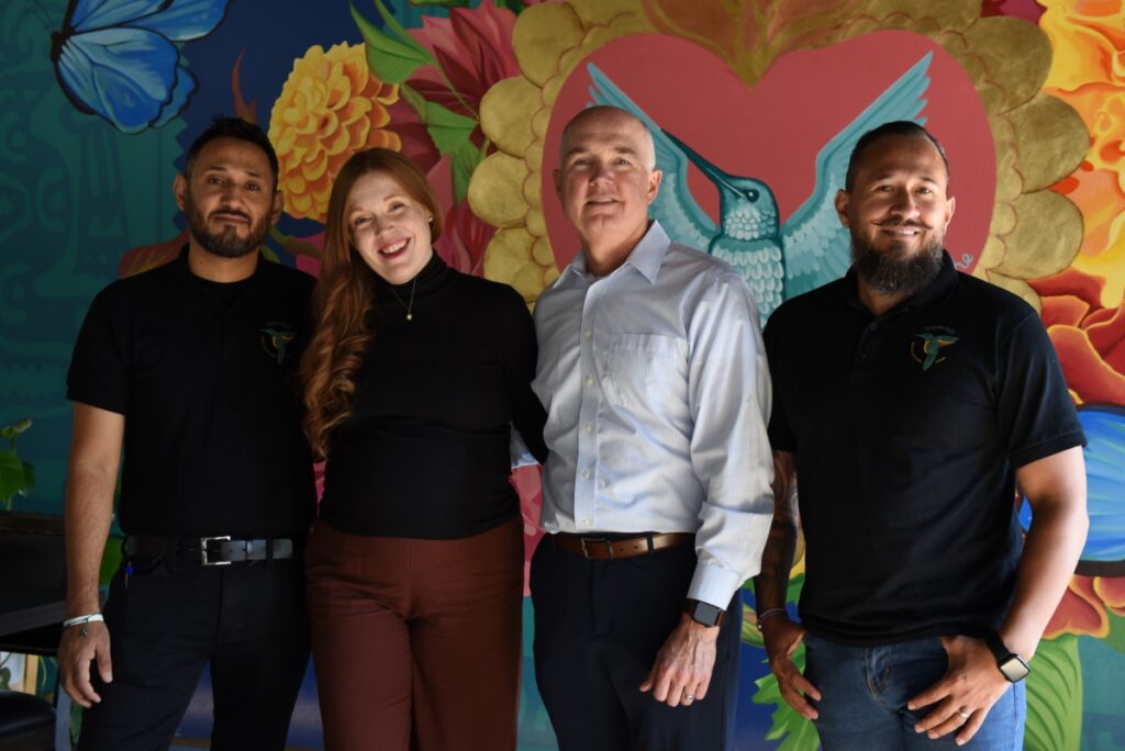 Owners Jovanny and Jesus Segoviano with Kayla and Joseph Welch in front of a colorful hummingbird mural at Tepache Mexican restaurant.