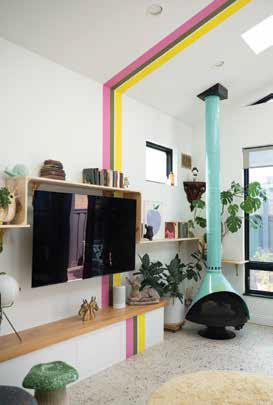 Brightly colored pink and yellow accent stripes on a white wall next to a wall-mounted TV and a retro teal fireplace.