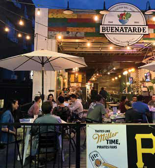 Buenatarde's outdoor patio illuminated at night with string lights as guests dine under umbrellas in Shadyside.