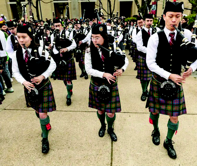 CMU bagpipers performing in traditional Scottish kilts and tartans during a university celebration.