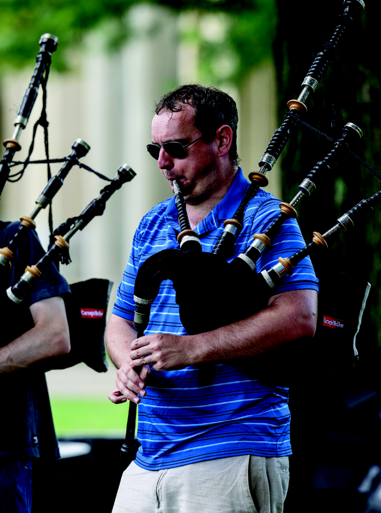 Professor Andrew Carlisle, Director of Bagpiping at CMU, playing the bagpipes during an outdoor rehearsal.