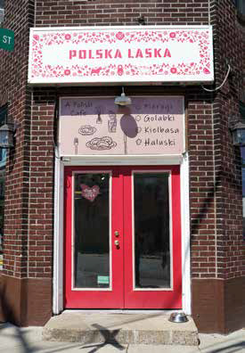 Exterior storefront of Polska Laska Polish café in Sharpsburg, featuring a brick building with bright red double doors and a decorative white sign.