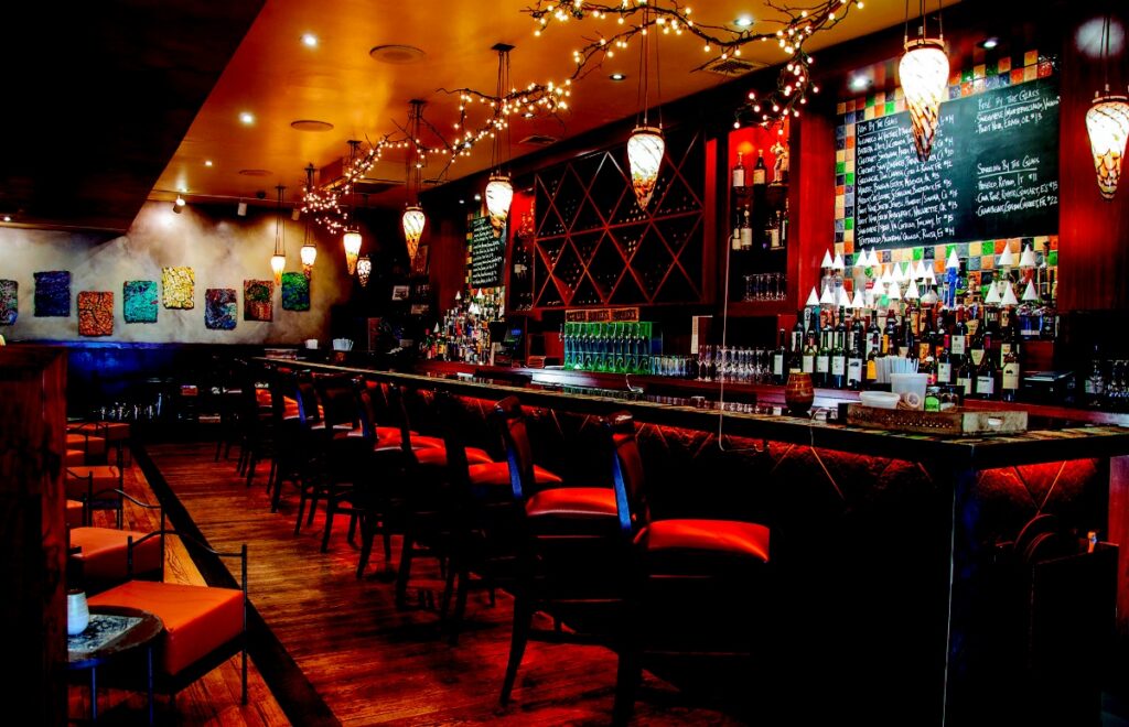 Elegant bar at Casbah in Shadyside with warm mood lighting, colorful mosaic tiles, a large wine selection, and red leather seating.