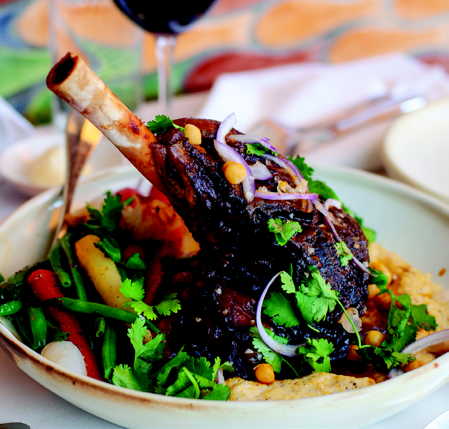 Mediterranean braised lamb shank served with heirloom grain grits, baby carrots, and asparagus at Casbah restaurant.