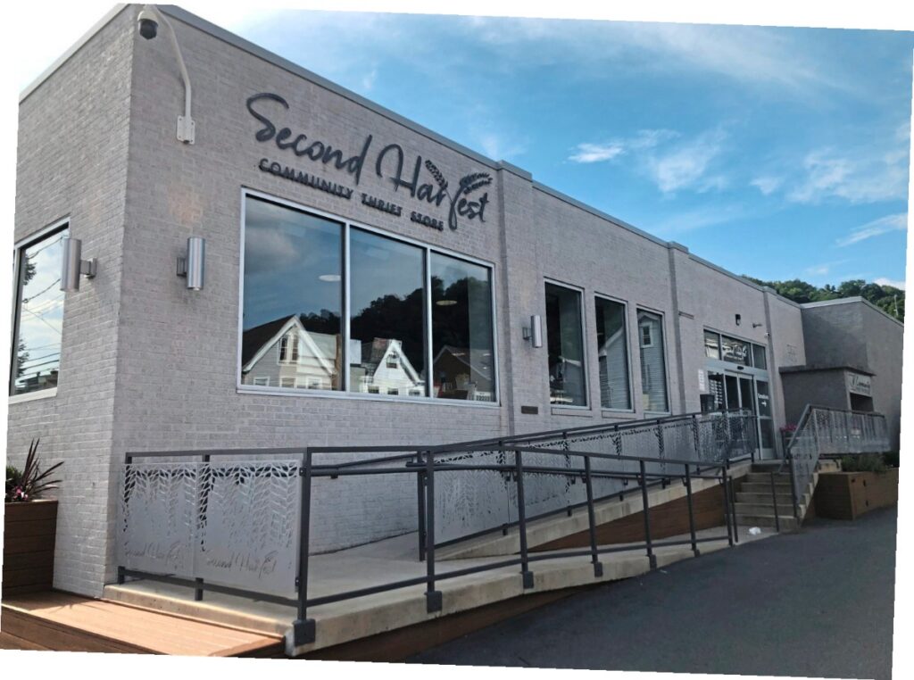 The modern gray brick exterior of Second Harvest Community Thrift Store featuring a large glass window and an accessible ramp entrance.