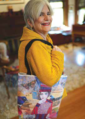 A close-up of Lauren Stern smiling while carrying a custom tote bag over her shoulder that features a print of her original collage artwork.