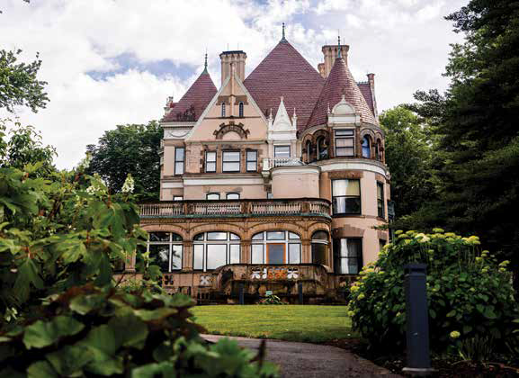 The historic Clayton mansion, a grand Gilded Age estate at The Frick Pittsburgh, surrounded by lush green trees and manicured lawns.