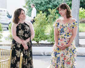 Amanda Dunyak Gillen in a floral dress talking with a colleague in a black and gold dress during an outdoor event at the museum.