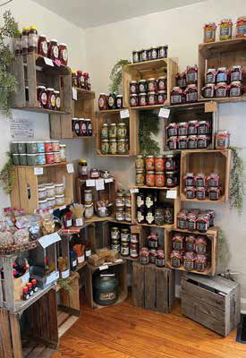 Rows of artisanal local honey jars and homemade preserves displayed beautifully on rustic wooden crate shelves inside a market.