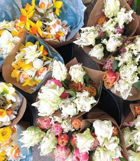 Several seasonal CSA flower bouquets wrapped in brown butcher paper, featuring colorful tulips and daffodils.