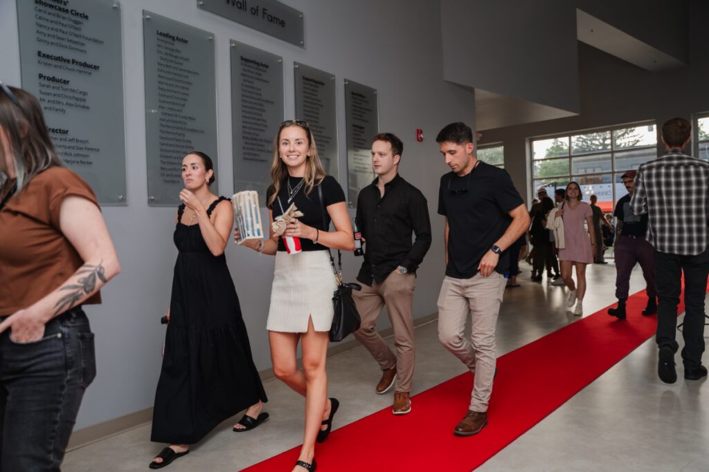 Moviegoers walking the red carpet with popcorn in the lobby of The Lindsay Theater.