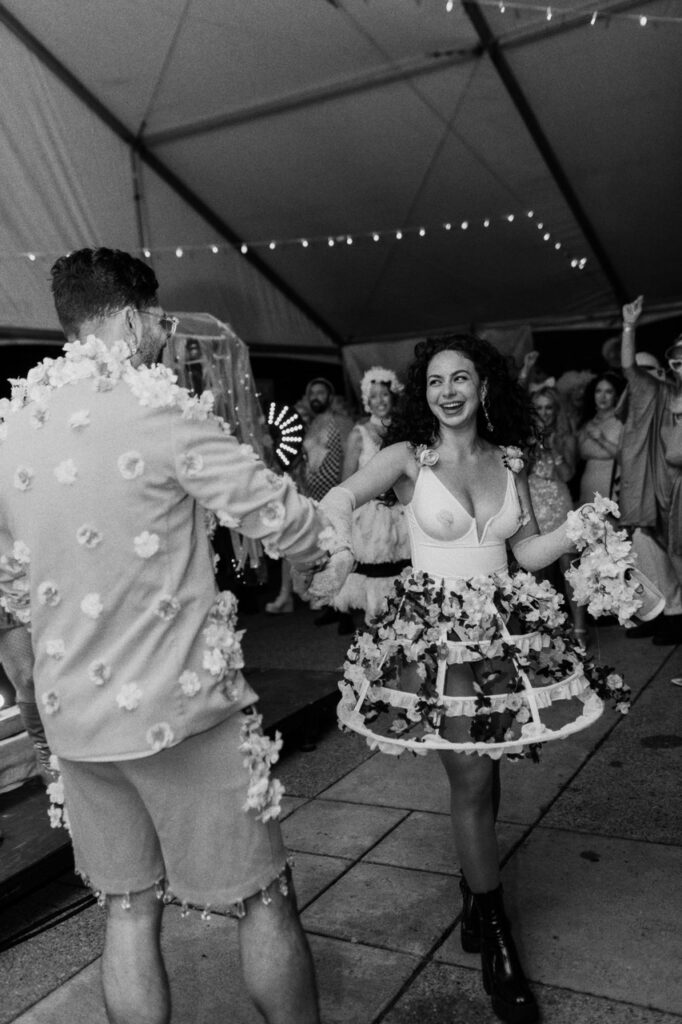 Two people dance at a garden party with their outfits covered in florals.