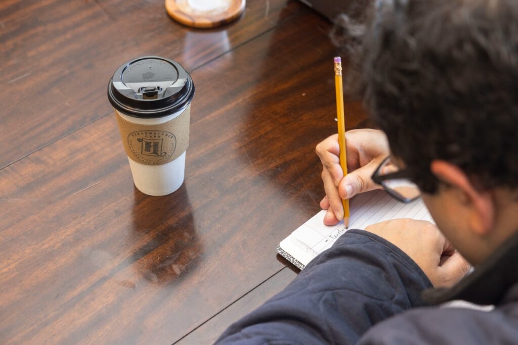 A group of local writers participating in a Shut Up and Write session in the cozy second-level workspace at Happenstance Cafe.