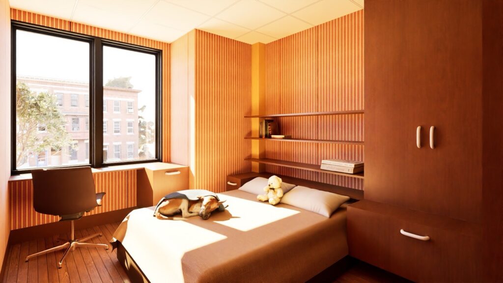 A mock up of a bedroom from Design House Homes with a dog laying on a bed, wood cabinets and shelves, and a desk and chair by two windows.