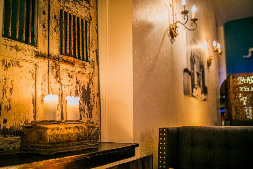 Warm candles glowing on a window sill against a rustic, reclaimed wood wall at Lula.