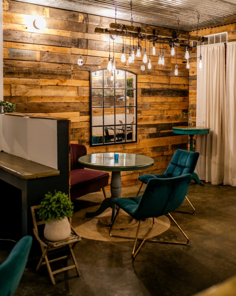 Cozy multi-level seating area with rustic wooden walls and hanging Edison bulb lighting at Ineffable Cà Phê.