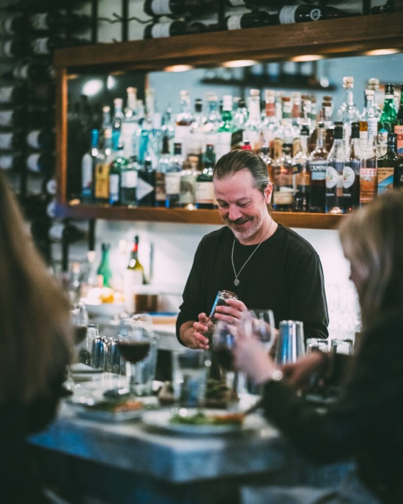 A smiling bartender preparing drinks behind the bar at Vivo Kitchen in Sewickley, PA.