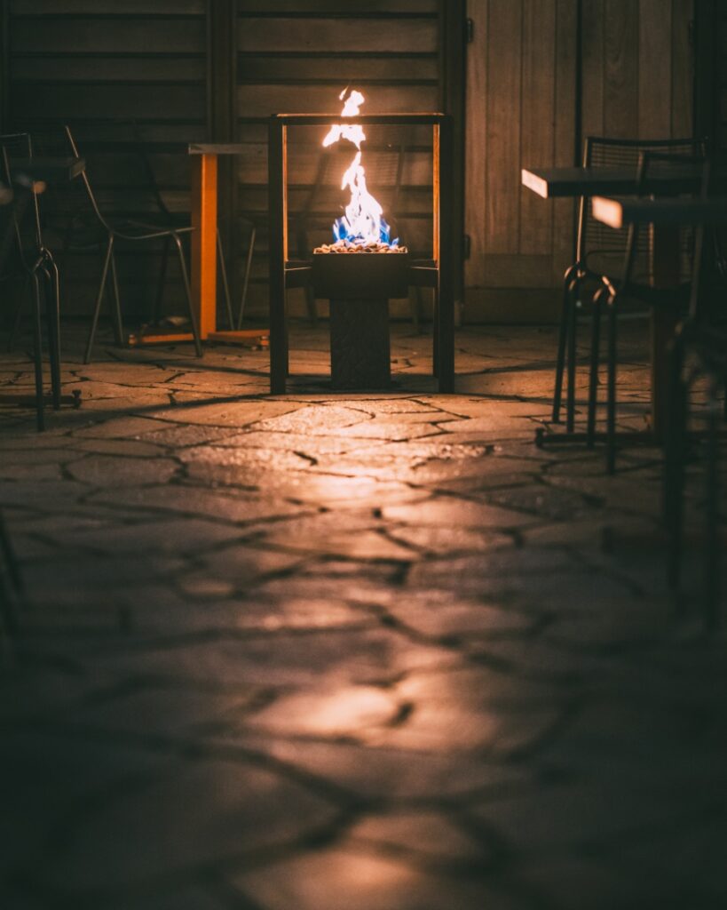 The quiet outdoor patio at Vivo Kitchen featuring a stone floor and a modern fire pit.