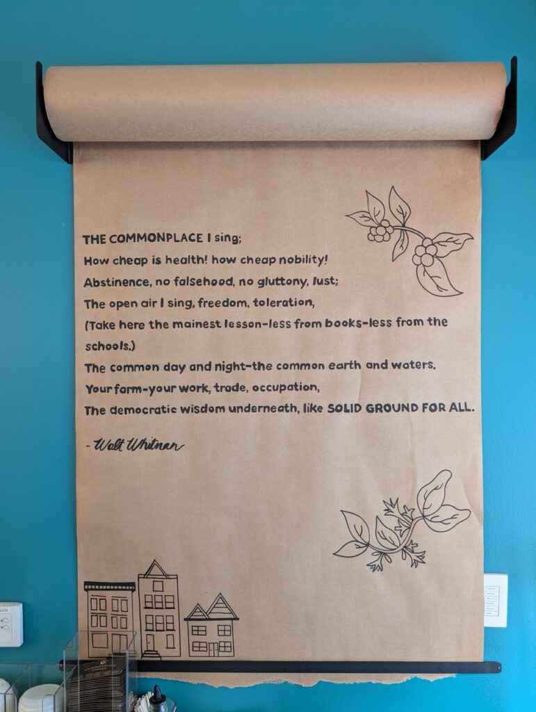 A scroll on the wall at Commonplace Coffee with a quote from Walt Whitman.