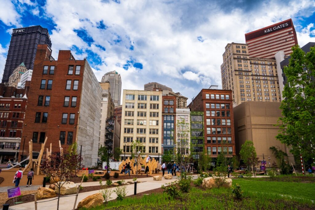 Green lawn, children's playground, and surrounding skyline views at Arts Landing in Pittsburgh.
