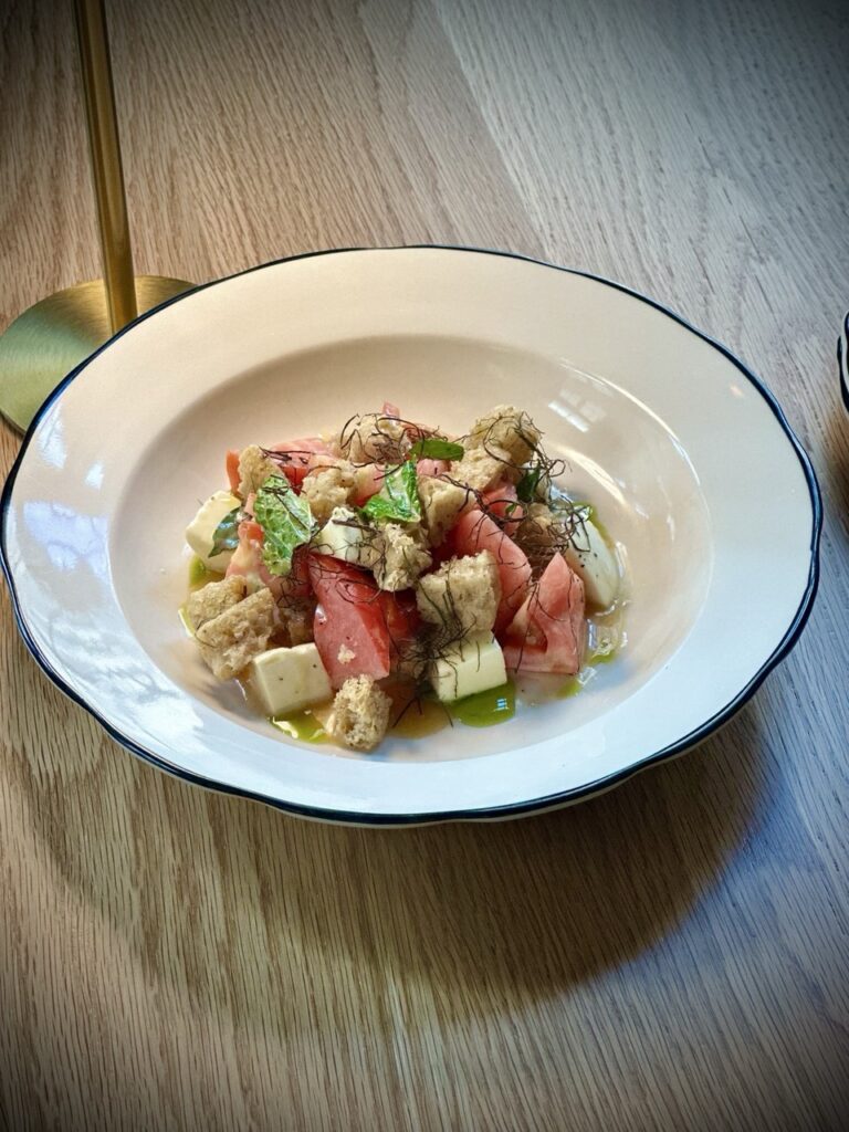 A white plate of chunks of tuna and bread with herbs on top.