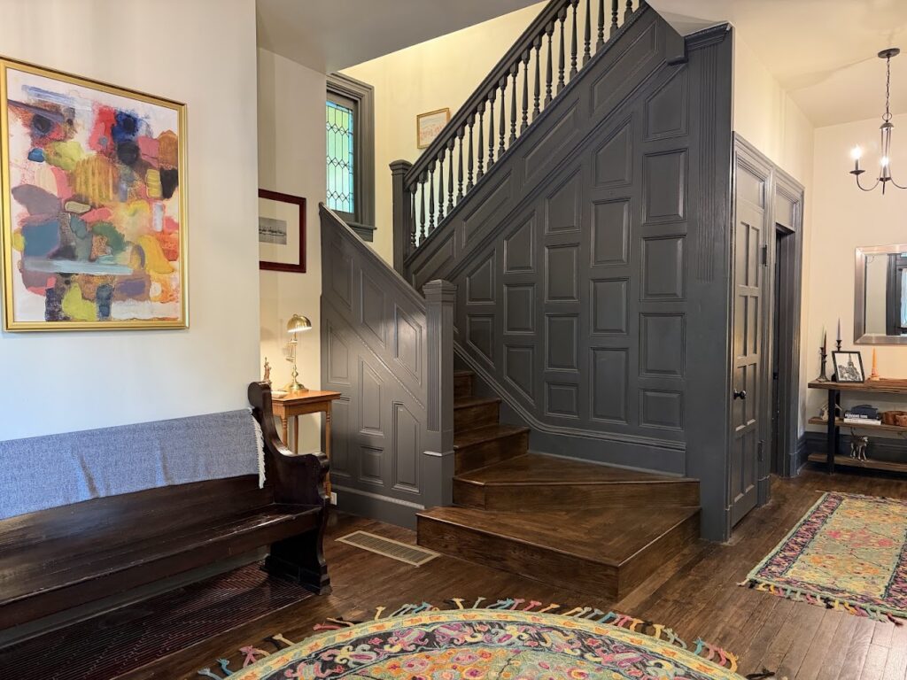 The inside of a house's foyer with a staircase and a wood floor.