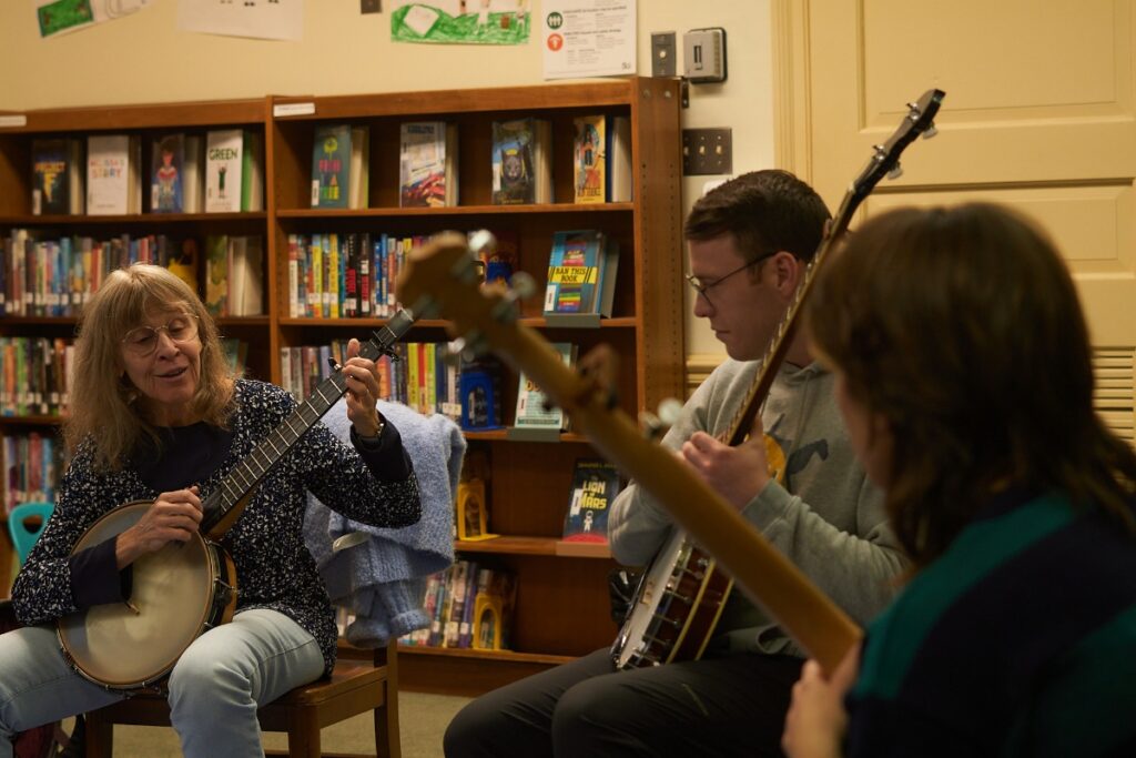 Musicians playing banjos together during a Calliope House folk music class in Pittsburgh.