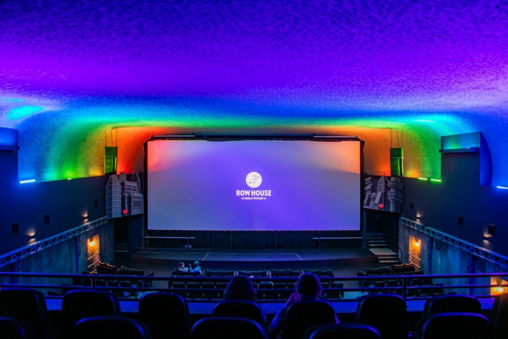View from the balcony showing a large cinema screen lit with colorful ambient lighting at Row House Hollywood.