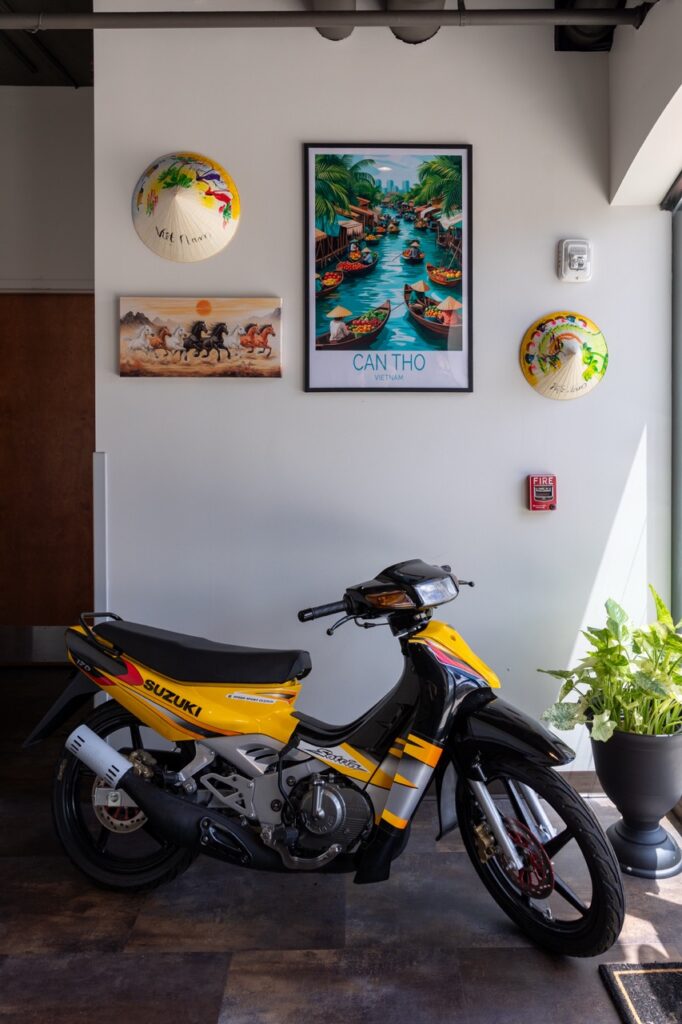 The interior of BeLa with a yellow scooter below a wall of Vietnamese art.