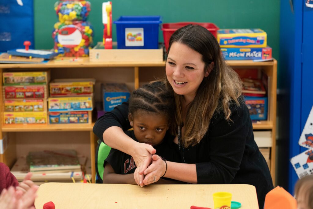 A woman and a young child sitting at table in a classroom.